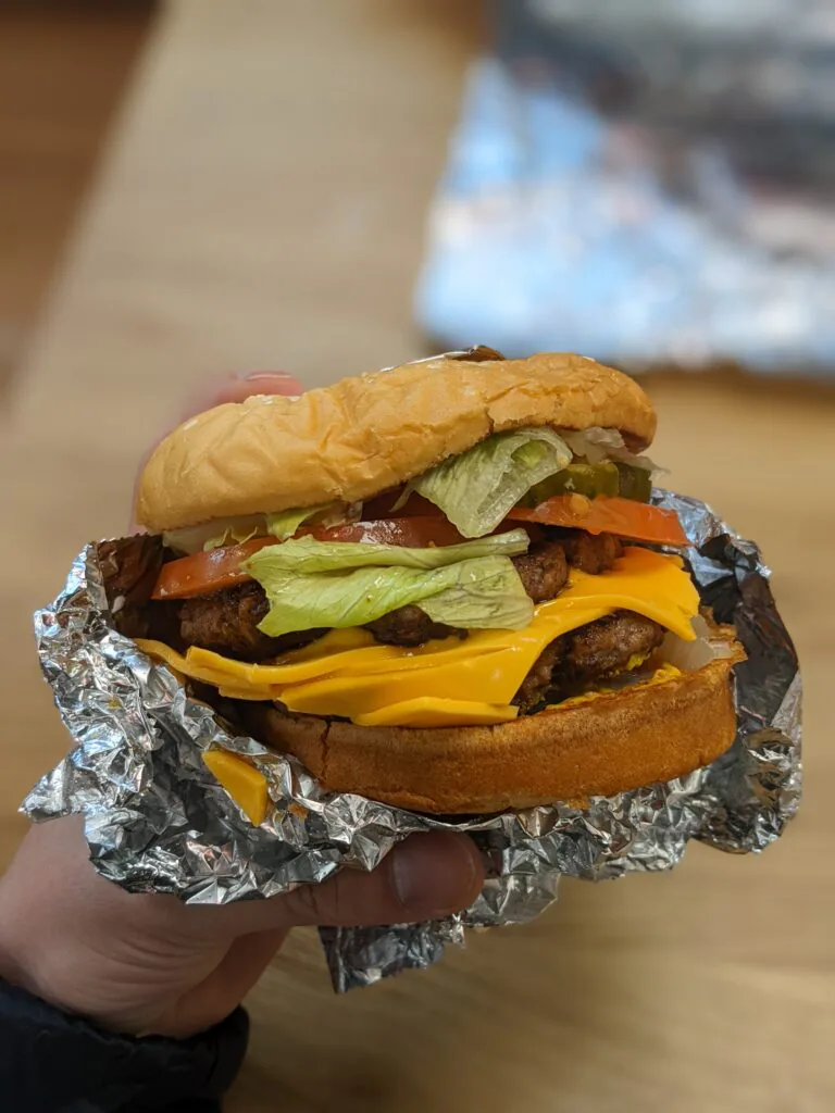 A Five Guys Cheeseburger with mayo, lettuce, pickles, tomatoes, grilled onions, grilled mushrooms, ketchup, mustard, relish and jalapenos.