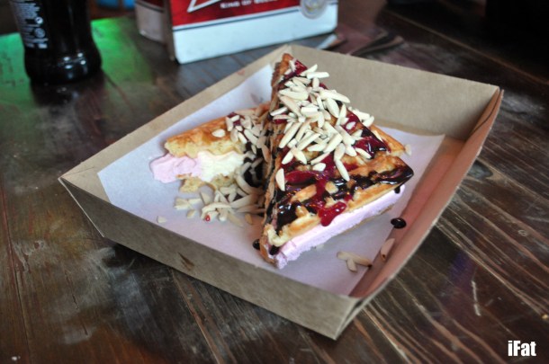 Nepolitan ice cream waffle sandwich with raspberry, almonds and chocolate sauce.